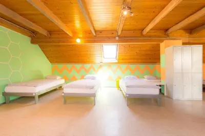 a room with three beds in a room with wooden ceilings at 1A Adventure Hostel in Lesce