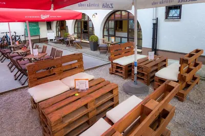 an outdoor seating area with wooden benches and an umbrella at 1A Adventure Hostel in Lesce