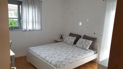 a white bedroom with a bed and a window at Apartment EMMA Ljubljana - FREE parking, AC, Wifi in Ljubljana