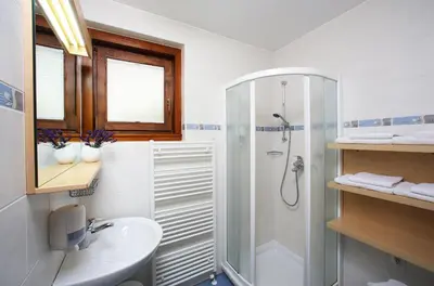 a white bathroom with a shower and a sink at Apartment Bernik II in Kranjska Gora