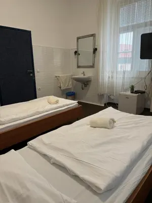 two beds in a room with a sink and a mirror at Guesthouse Pri Tonetu in Ptuj