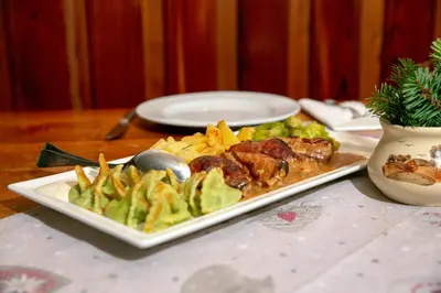 a plate of food with meat and vegetables on a table at Govc-Vršnik in Solčava