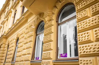 a building with three windows with a purple sign on it at 4flats in Maribor