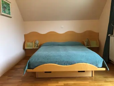 a bedroom with a large bed with a wooden headboard at Apartments Alpha Center in Bovec