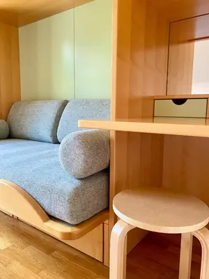 a small room with a bed and a stool at Apartments Alpha Center in Bovec
