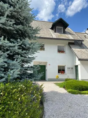 a white house with a tree in front of it at Apartments Alpha Center in Bovec