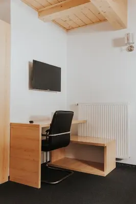 an office with a desk with a chair and a tv at Hotel House Rozka in Cerklje na Gorenjskem