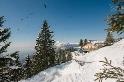 a snow covered mountain with a house in the background at Hotel House Rozka in Cerklje na Gorenjskem