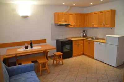 a kitchen with wooden cabinets and a table and a table and chairs at Apartmaji Srnca in Cerkno