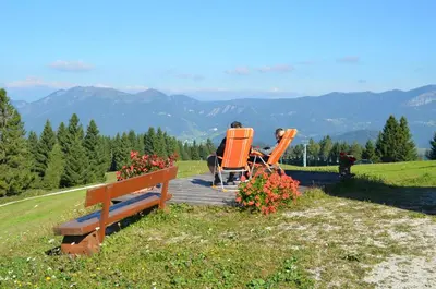 a couple of people sitting in chairs on a bench at Apartmaji Srnca in Cerkno