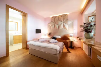 a bedroom with a large bed in a room with pink walls at Škrabčeva domačija in Ribnica