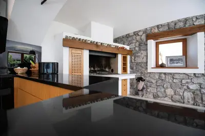 a kitchen with a black counter top and a stone wall at Škrabčeva domačija in Ribnica