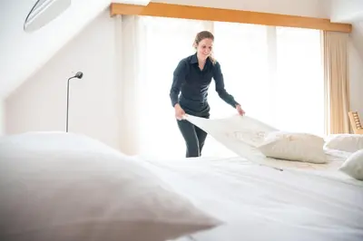a woman is standing on a bed next to a window at Škrabčeva domačija in Ribnica