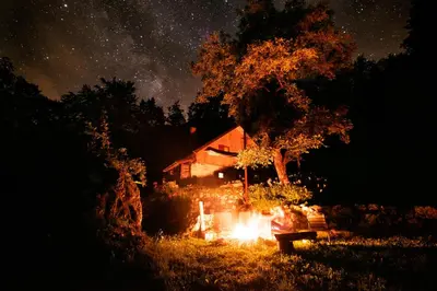 a person sitting at a table under a tree at night at Miha lodge - Mihčevo pleče in Soča