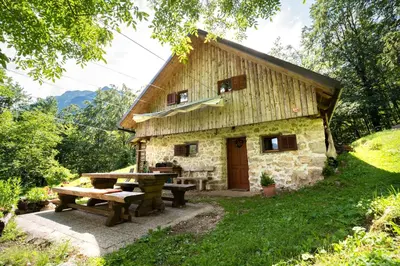 a stone house with a picnic table in front of it at Miha lodge - Mihčevo pleče in Soča