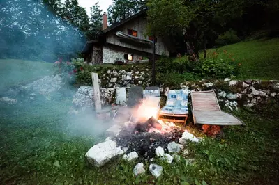a fire in a yard with a bench next to a house at Miha lodge - Mihčevo pleče in Soča