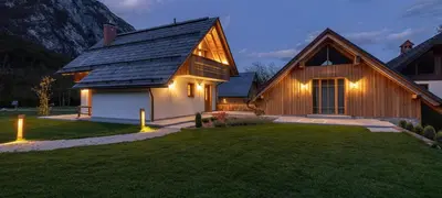 a wooden house with lights on the lawn at PRIVILLAGE Stare - Villa & Chalet in Bohinj