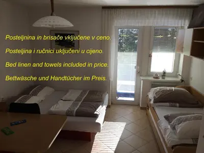 a bedroom with two beds and a table and a window at Apartment Gaber 82 in Zreče