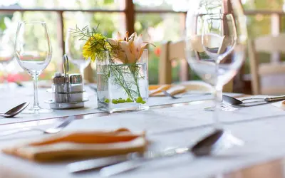 a table with glasses and a vase with flowers on it at Apartmaji Smogavc in Zreče