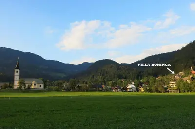 a green field with a village and a church at Villa Bohinca in Bohinj