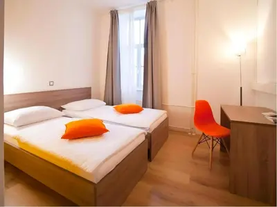 two beds in a room with a desk and a chair at B&B HOTEL Maribor UNI Hostel in Maribor