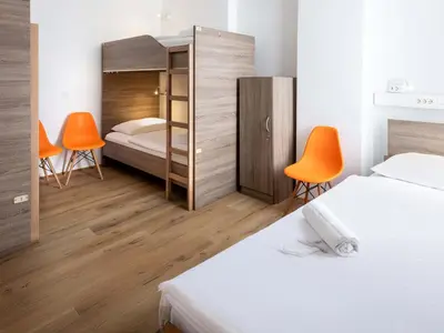 a bedroom with a bed and two orange chairs at B&B HOTEL Maribor UNI Hostel in Maribor