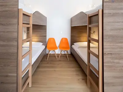 a room with two bunk beds and two orange chairs at B&B HOTEL Maribor UNI Hostel in Maribor