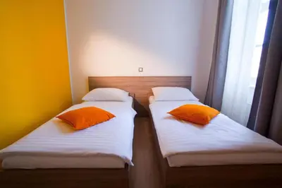 two beds with orange pillows in a room at B&B HOTEL Maribor UNI Hostel in Maribor