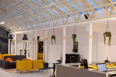 an office lobby with yellow chairs and a table at B&B HOTEL Maribor UNI Hostel in Maribor