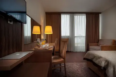 a hotel room with a desk and a bedroom at Hotel Kras in Postojna
