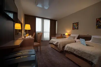 a hotel room with two beds and a flat screen tv at Hotel Kras in Postojna