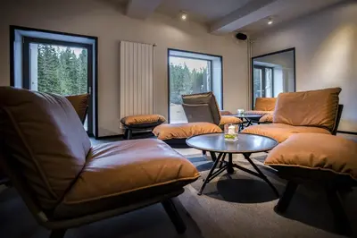 a living room with couches and a table and windows at Hotel Pokljuka in Goreljek