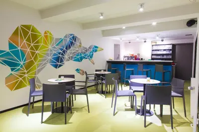 a restaurant with tables and chairs and a mural at Hotel Pokljuka in Goreljek