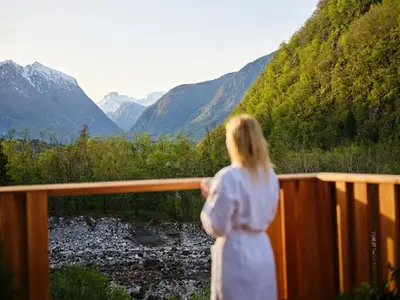 a woman standing on a balcony looking at the mountains at Hotel Boka in Bovec