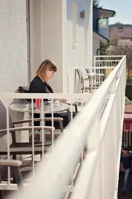 a woman sitting at a table on a balcony at Hotel Bajt Maribor in Maribor
