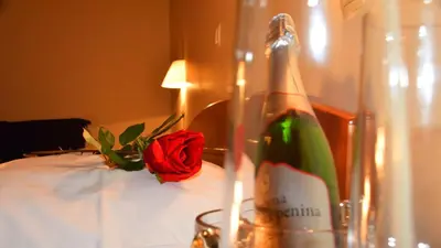 a bottle of champagne and a rose on a bed at Hotel Bajt Maribor in Maribor