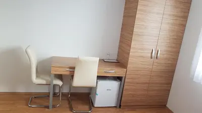 a desk with a chair and a table and cabinets at B&B By The Way in Ljubljana