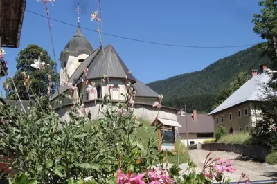 a building with a clock tower and flowers in the foreground at Apartments Julian Experience in Rateče