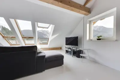 a living room with a couch and a tv and windows at Apartments Julian Experience in Rateče