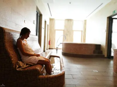 a woman sitting on a wicker bench in a building at Wellness Hotel Montis in Mozirje