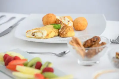 a table with a plate of food and a plate of fruit at Wellness Hotel Montis in Mozirje