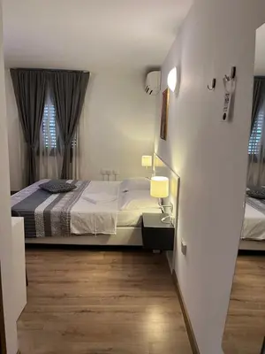 a small bedroom with a bed and two windows at Hotel Paquito in Nova Gorica