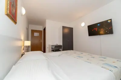 a bedroom with two beds and a tv on the wall at Hotel Paquito in Nova Gorica