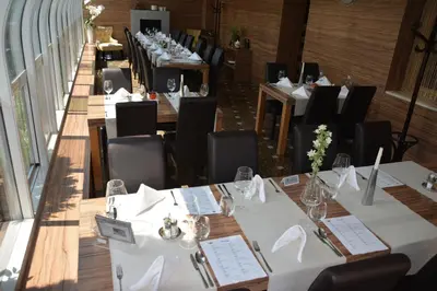 a row of tables in a restaurant with white tables and chairs at Gostilna in motel Pri Lešniku in Maribor