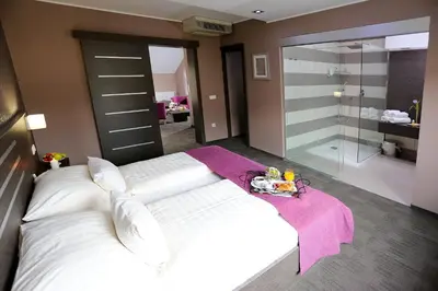 a bedroom with a large white bed and a glass shower at Gostilna in motel Pri Lešniku in Maribor