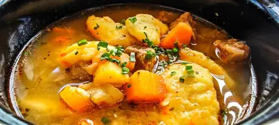 a bowl of soup with potatoes and carrots in it at Hotel Celjska Koca in Celje