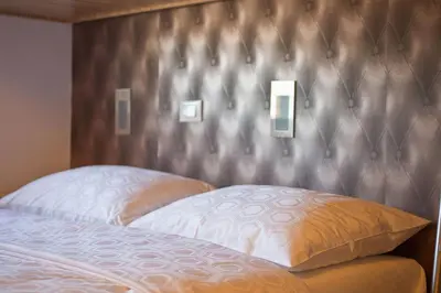 a bed with a headboard with two pillows on it at Bit Center Hotel in Ljubljana