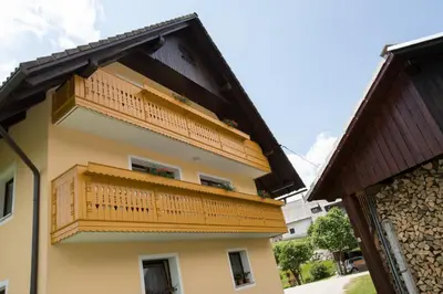 a yellow building with a wooden balcony on it at Apartmaji Matej Cvetek in Bohinj
