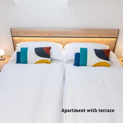a bed with white sheets and pillows at Apartmaji Taler in Bohinj