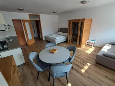 a kitchen and a living room with a table and chairs at Apartment Honey Bee with SAUNA in Kobarid